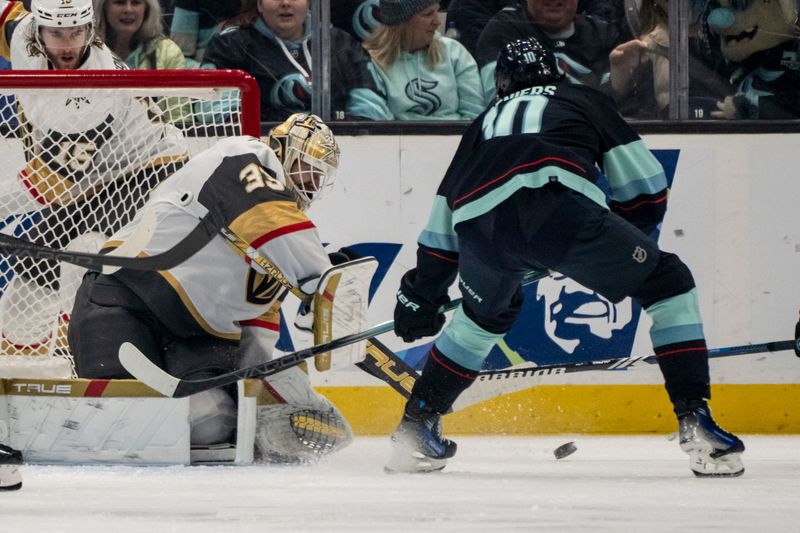 Mar 12, 2024; Seattle, Washington, USA; Vegas Golden Knights goalie Adin Hill (33) knocks the puck away from Seattle Kraken forward Matty Beniers (10) during the first period at Climate Pledge Arena. Mandatory Credit: Stephen Brashear-USA TODAY Sports