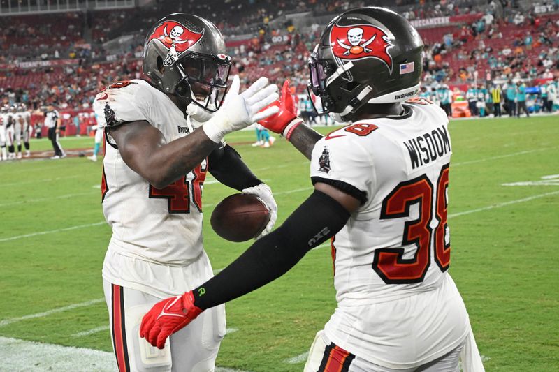 Tampa Bay Buccaneers linebacker Antonio Grier Jr. (48) and safety Rashad Wisdom (38) celebrate at the end of a pre season NFL football game against the Miami Dolphins, Friday, Aug. 23, 2024, in Tampa, Fla. The Buccaneers defeated the Dolphins 24-14. (AP Photo/Jason Behnken)