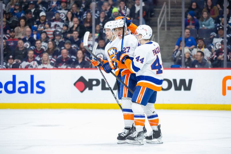 Jan 16, 2024; Winnipeg, Manitoba, CAN; New York Islanders forward Anders Lee (27) is congratulated by his teammates on his goal against Winnipeg Jets goalie Connor Hellebuyck (37) during the first period at Canada Life Centre. Mandatory Credit: Terrence Lee-USA TODAY Sports