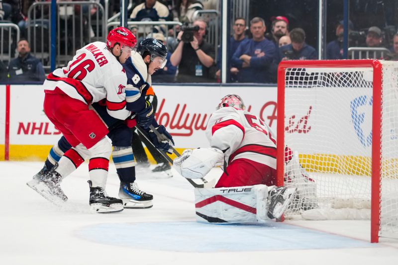 Nov 23, 2024; Columbus, Ohio, USA;  Carolina Hurricanes defenseman Sean Walker (26) skates for the puck against Columbus Blue Jackets defenseman Zach Werenski (8) as they collide with Carolina Hurricanes goaltender Pyotr Kochetkov (52) in the third period at Nationwide Arena. Mandatory Credit: Aaron Doster-Imagn Images