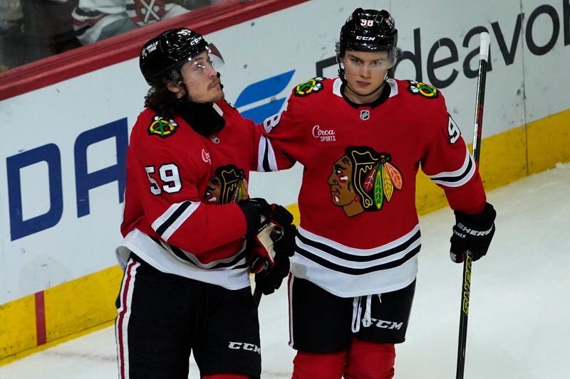 Oct 22, 2024; Chicago, Illinois, USA; Chicago Blackhawks left wing Tyler Bertuzzi (59) celebrates his goal against the Vancouver Canucks with center Connor Bedard (98) during the third period at United Center. Mandatory Credit: David Banks-Imagn Images