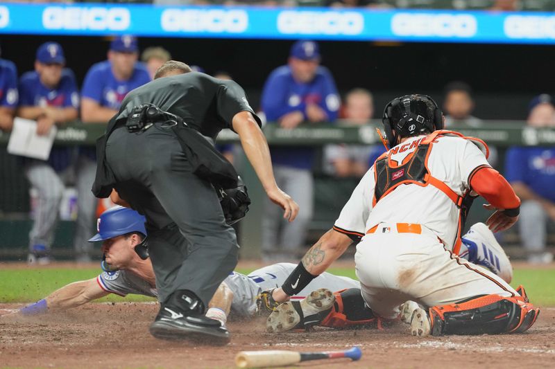 Jun 24, 2025; Baltimore, Maryland, USA; Texas Rangers outfielder Evan Carter (32) slides safely to score the game winning run during the tenth inning ahead of a tag by Baltimore Orioles catcher Gary Sanchez (99) at Oriole Park at Camden Yards. Mandatory Credit: Mitch Stringer-Imagn Images