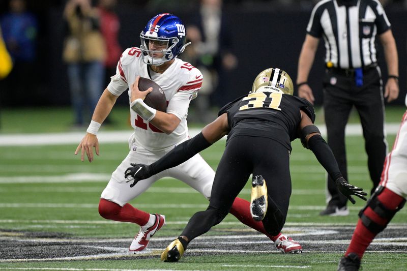 New York Giants quarterback Tommy DeVito (15) runs with the ball as New Orleans Saints safety Jordan Howden (31) defends during the first half of an NFL football game Sunday, Dec. 17, 2023, in New Orleans. (AP Photo/Matthew Hinton)