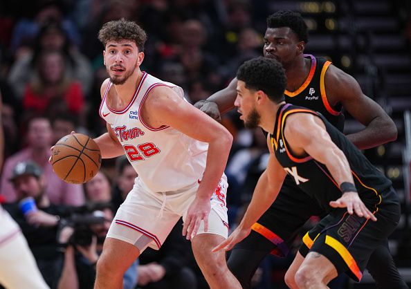 HOUSTON, TEXAS - DECEMBER 27: Alperen Sengun #28 of the Houston Rockets dribbles the ball as Devin Booker #1 and Udoka Azubuike #27 of the Phoenix Suns defend during the second quarter of the game at Toyota Center on December 27, 2023 in Houston, Texas. User expressly acknowledges and agrees that, by downloading and or using this photograph, User is consenting to the terms and conditions of the Getty Images License Agreement. (Photo by Alex Bierens de Haan/Getty Images)