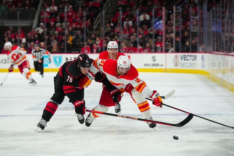 Mar 10, 2024; Raleigh, North Carolina, USA;  Carolina Hurricanes defenseman Brady Skjei (76) pokes the puck away from Calgary Flames center Nazem Kadri (91) during the second period at PNC Arena. Mandatory Credit: James Guillory-USA TODAY Sports