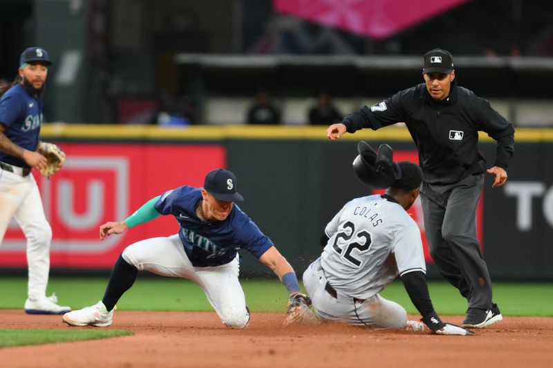 Jun 13, 2024; Seattle, Washington, USA; Seattle Mariners third baseman Dylan Moore (25) tags out Chicago White Sox right fielder Oscar Colas (22) during a steal attempt in the ninth inning at T-Mobile Park. Mandatory Credit: Steven Bisig-USA TODAY Sports