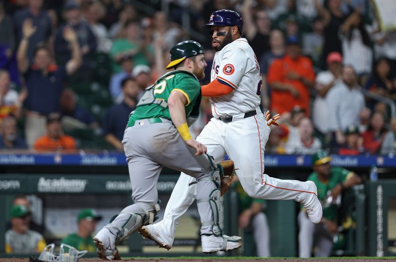 May 16, 2024; Houston, Texas, USA; Houston Astros first baseman Jon Singleton (28) scores a run past Oakland Athletics catcher Kyle McCann (52) during the third inning at Minute Maid Park. Mandatory Credit: Troy Taormina-USA TODAY Sports