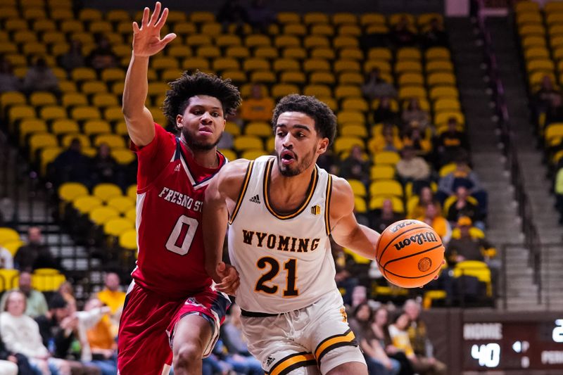 Jan 31, 2023; Laramie, Wyoming, USA; Wyoming Cowboys guard Noah Reynolds (21) drives against Fresno State Bulldogs guard Donavan Yap (0) during the first half at Arena-Auditorium. Mandatory Credit: Troy Babbitt-USA TODAY Sports