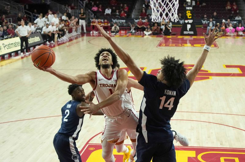 Feb 11, 2025; Los Angeles, California, USA; Southern California Trojans guard Desmond Claude (1) shoots the ball against Penn State Nittany Lions forward Yanic Konan Niederhauser (14) and guard D'Marco Dunn (2) in the second half at Galen Center. Mandatory Credit: Kirby Lee-Imagn Images