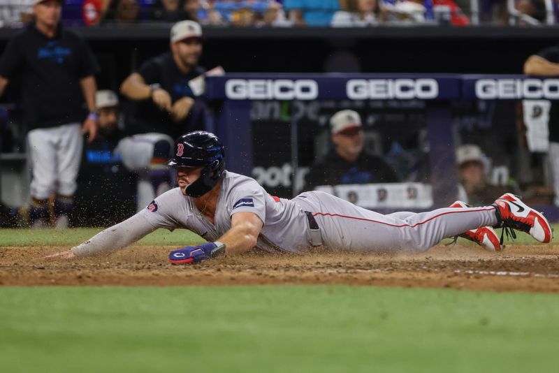 Jul 4, 2024; Miami, Florida, USA; Boston Red Sox first baseman Romy Gonzalez (23) slides at home plate and scores against the Miami Marlins during the twelfth inning at loanDepot Park. Mandatory Credit: Sam Navarro-USA TODAY Sports