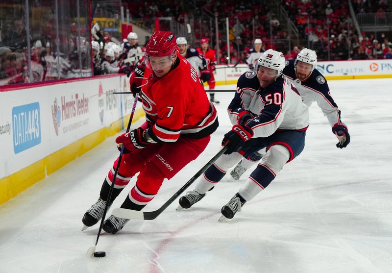 Nov 26, 2023; Raleigh, North Carolina, USA;  Carolina Hurricanes defenseman Dmitry Orlov (7) is chased by Columbus Blue Jackets left wing Eric Robinson (50) during the second period at PNC Arena. Mandatory Credit: James Guillory-USA TODAY Sports