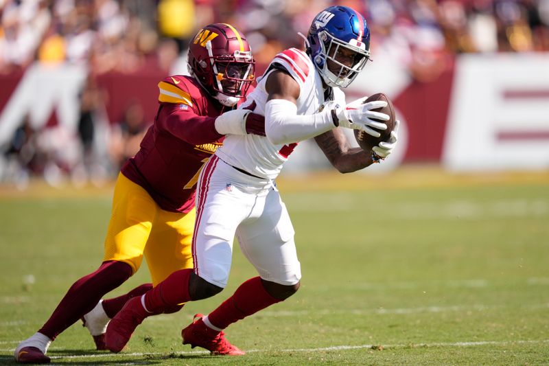 New York Giants wide receiver Malik Nabers, right, stretches for a first down as he is tackled by Washington Commanders cornerback Noah Igbinoghene, left, during the second half of an NFL football game in Landover, Md., Sunday, Sept. 15, 2024. (AP Photo/Matt Slocum)