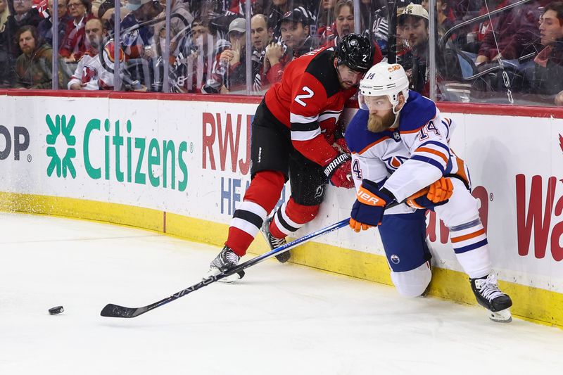 Dec 21, 2023; Newark, New Jersey, USA; Edmonton Oilers defenseman Mattias Ekholm (14) passes the puck while being defended by New Jersey Devils defenseman Brendan Smith (2) during the first period at Prudential Center. Mandatory Credit: Ed Mulholland-USA TODAY Sports