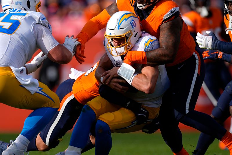 Los Angeles Chargers quarterback Justin Herbert (10) is tackled after a short gain during the second half of an NFL football game against the Denver Broncos, Sunday, Oct. 13, 2024, in Denver. (AP Photo/David Zalubowski)