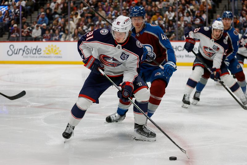 Jan 10, 2026; Denver, Colorado, USA; Columbus Blue Jackets center Kent Johnson (91) controls the puck ahead of Colorado Avalanche defenseman Josh Manson (42) in the third period at Ball Arena. Mandatory Credit: Isaiah J. Downing-Imagn Images