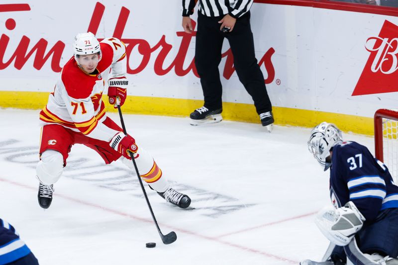 Oct 2, 2024; Winnipeg, Manitoba, CAN;  Calgary Flames forward Walker Duehr (71) skates in on Winnipeg Jets goalie Connor Hellebuyck (37) during the third period at Canada Life Centre. Mandatory Credit: Terrence Lee-Imagn Images