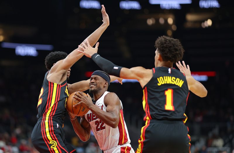 ATLANTA, GEORGIA - APRIL 09:  Jimmy Butler #22 of the Miami Heat drives between De'Andre Hunter #12 and Jalen Johnson #1 of the Atlanta Hawks during the first quarter at State Farm Arena on April 09, 2024 in Atlanta, Georgia.  NOTE TO USER: User expressly acknowledges and agrees that, by downloading and/or using this photograph, user is consenting to the terms and conditions of the Getty Images License Agreement.  (Photo by Kevin C. Cox/Getty Images)