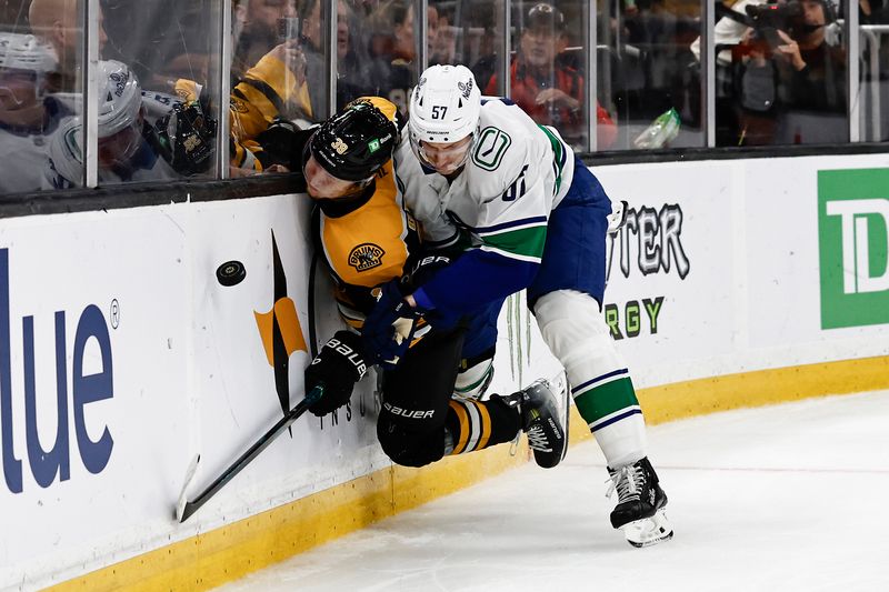 Nov 26, 2024; Boston, Massachusetts, USA; Vancouver Canucks defenseman Tyler Myers (57) checks Boston Bruins center Morgan Geekie (39) into the boards during the third period at TD Garden. Mandatory Credit: Winslow Townson-Imagn Images