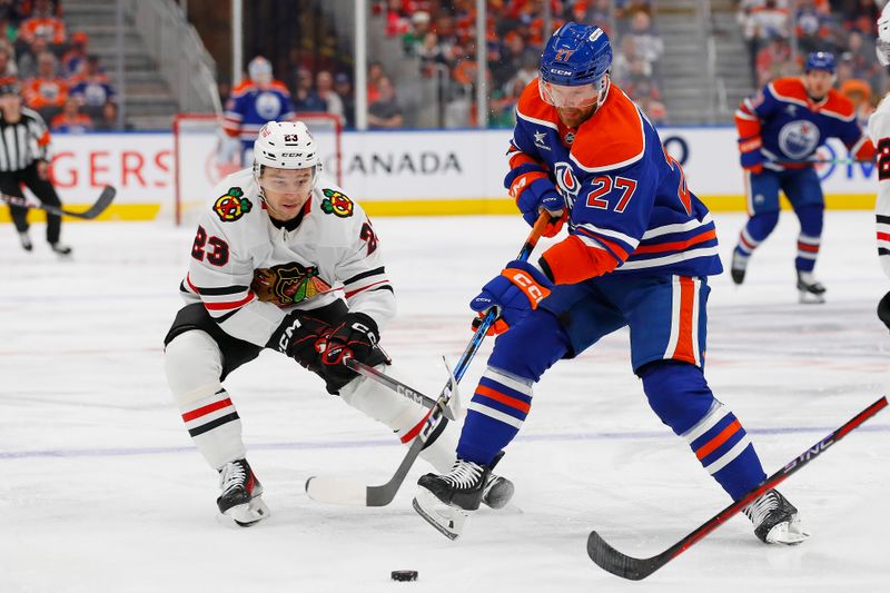 Oct 12, 2024; Edmonton, Alberta, CAN; Edmonton Oilers defensemen Brett Kulak (27)  and Chicago Blackhawks forward Philipp Kurashev (23) battle for a loose puck during the first period at Rogers Place. Mandatory Credit: Perry Nelson-Imagn Images