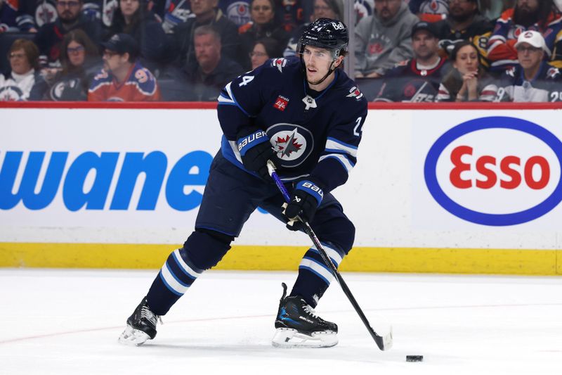 Apr 13, 2025; Winnipeg, Manitoba, CAN; Winnipeg Jets defenseman Haydn Fleury (24) gets set to shoot the puck up the ice in a game against the Edmonton Oilers in the first period at Canada Life Centre. Mandatory Credit: James Carey Lauder-Imagn Images