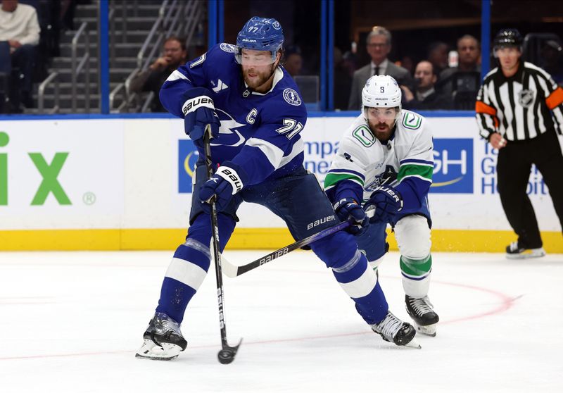 Oct 15, 2024; Tampa, Florida, USA; Tampa Bay Lightning defenseman Victor Hedman (77) passes the puck as Vancouver Canucks right wing Conor Garland (8) defends during the second period at Amalie Arena. Mandatory Credit: Kim Klement Neitzel-Imagn Images