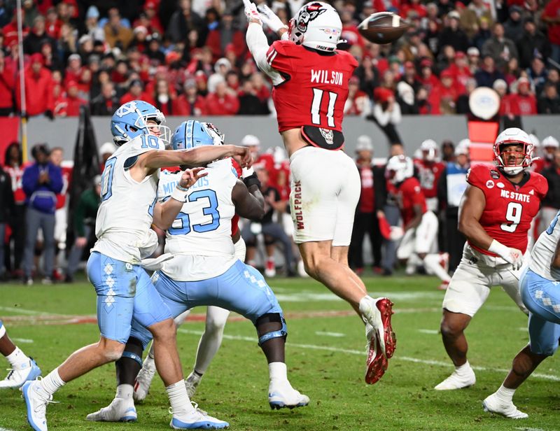 Nov 25, 2023; Raleigh, North Carolina, USA; North Carolina Tar Heels quarterback Drake Maye (10) throws a pass against North Carolina State Wolfpack linebacker Payton Wilson (11) during the first half at Carter-Finley Stadium. Mandatory Credit: Rob Kinnan-USA TODAY Sports