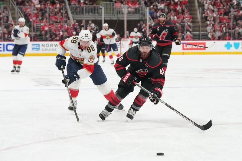 May 20, 2025; Raleigh, North Carolina, USA;  Carolina Hurricanes forward Jordan Martinook (48) and Florida Panthers defenseman Nate Schmidt (88) skate toward the puck during the second period in game one of the Eastern Conference Final of the 2025 Stanley Cup Playoffs at Lenovo Center. Mandatory Credit: James Guillory-Imagn Images