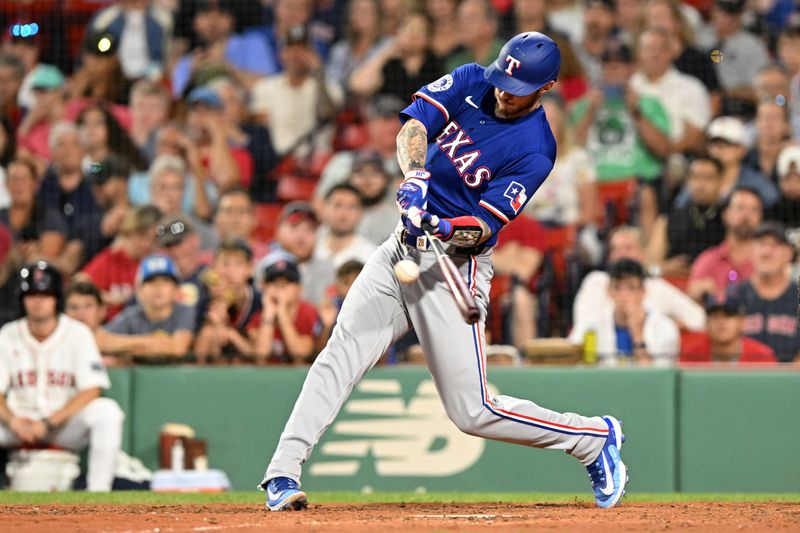 Aug 14, 2024; Boston, Massachusetts, USA; Texas Rangers catcher Jonah Heim (28) hits a two-run home run against the Boston Red Sox during the tenth inning at Fenway Park. Mandatory Credit: Brian Fluharty-USA TODAY Sports