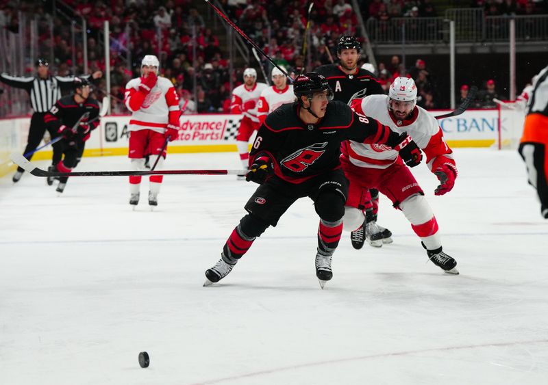 Jan 19, 2024; Raleigh, North Carolina, USA;  Carolina Hurricanes left wing Teuvo Teravainen (86) and Detroit Red Wings center Robby Fabbri (14) chase after the puck during the second period at PNC Arena. Mandatory Credit: James Guillory-USA TODAY Sports