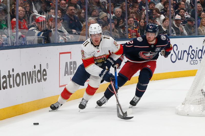 Mar 5, 2026; Columbus, Ohio, USA; Florida Panthers right wing Mackie Samoskevich (11) passes the puck as Columbus Blue Jackets defenseman Jake Christiansen (2) trails the play during the first period at Nationwide Arena. Mandatory Credit: Russell LaBounty-Imagn Images
