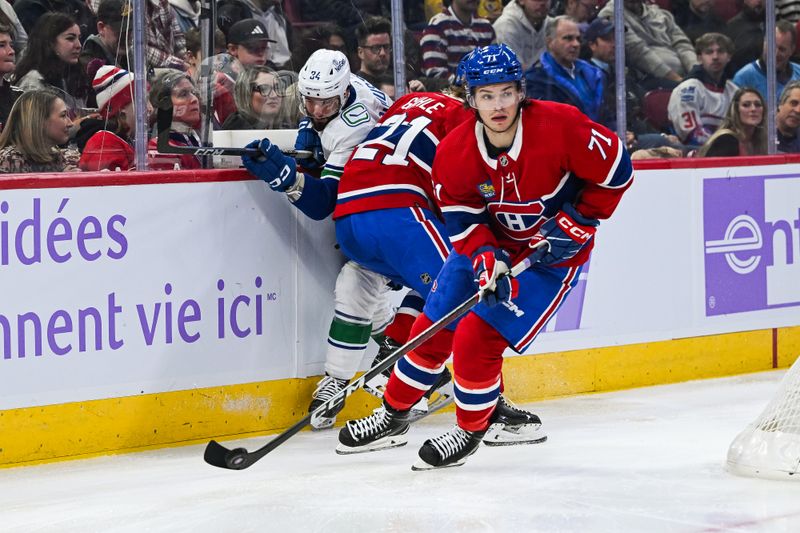 Nov 12, 2023; Montreal, Quebec, CAN; Montreal Canadiens center Jake Evans (71) skates away with the puck as defenseman Kaiden Guhle (21) checks Vancouver Canucks left wing Phillip Di Giuseppe (34) in the back during the first period at Bell Centre. Mandatory Credit: David Kirouac-USA TODAY Sports