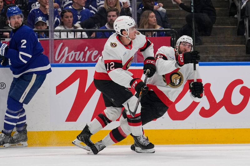 Apr 20, 2025; Toronto, Ontario, CAN; Ottawa Senators forward Shane Pinto (12) and forward Michael Amadio (22) collide as Toronto Maple Leafs defenceman Simon Benoit (2) looks on during the second period of game one of the first round of the 2025 Stanley Cup Playoffs at Scotiabank Arena. Mandatory Credit: John E. Sokolowski-Imagn Images