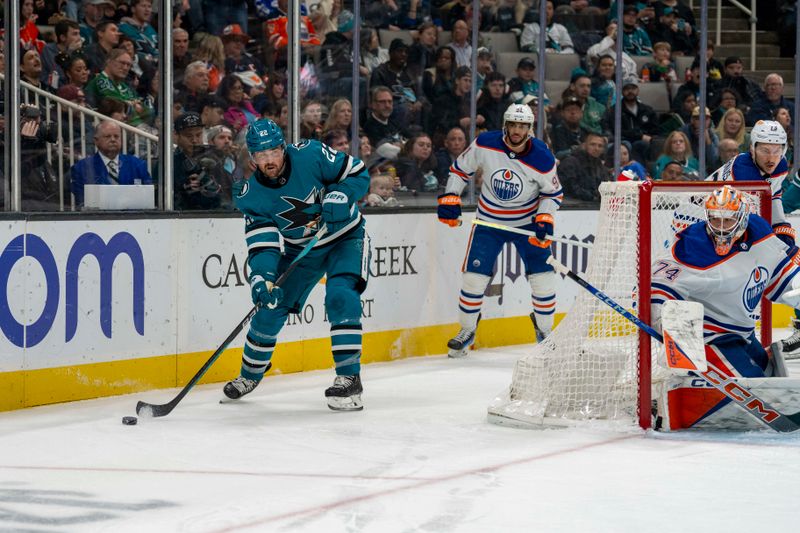 Dec 28, 2023; San Jose, California, USA; San Jose Sharks center Ryan Carpenter (22) skates with the puck behind the net against Edmonton Oilers center Connor McDavid (97) during the second period at SAP Center at San Jose. Mandatory Credit: Neville E. Guard-USA TODAY Sports