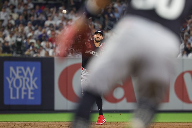 Jun 5, 2024; Bronx, New York, USA; Minnesota Twins shortstop Carlos Correa (4) throws the ball to first baseman Carlos Santana (30) for an out during the sixth inning against the New York Yankees at Yankee Stadium. Mandatory Credit: Vincent Carchietta-USA TODAY Sports