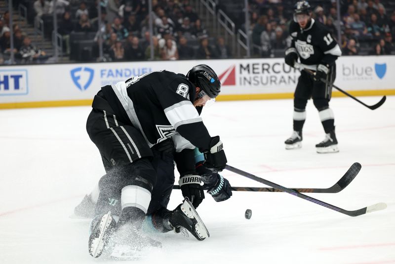 Nov 23, 2024; Los Angeles, California, USA;  Los Angeles Kings defenseman Vladislav Gavrikov (84) and Seattle Kraken defenseman Adam Larsson (6) fight for the puck during the first period at Crypto.com Arena. Mandatory Credit: Kiyoshi Mio-Imagn Images