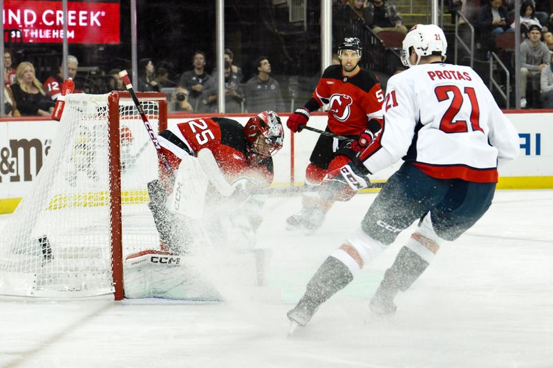 Oct 19, 2024; Newark, New Jersey, USA; New Jersey Devils goaltender Jacob Markstrom (25) makes a save against Washington Capitals center Aliaksei Protas (21) during the first period at Prudential Center. Mandatory Credit: John Jones-Imagn Images