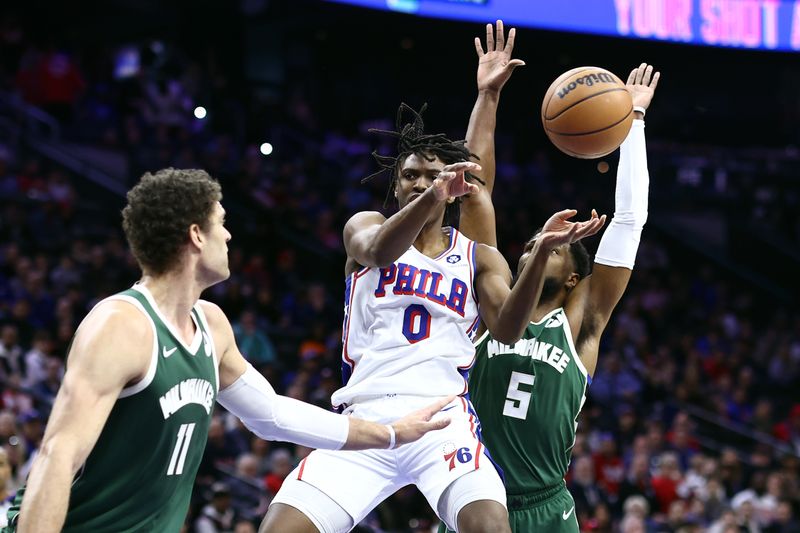 PHILADELPHIA, PENNSYLVANIA - FEBRUARY 25: Tyrese Maxey #0 of the Philadelphia 76ers passes the ball between Brook Lopez #11 and Malik Beasley #5 of the Milwaukee Bucks during the first quarter  at the Wells Fargo Center on February 25, 2024 in Philadelphia, Pennsylvania. (Photo by Tim Nwachukwu/Getty Images)