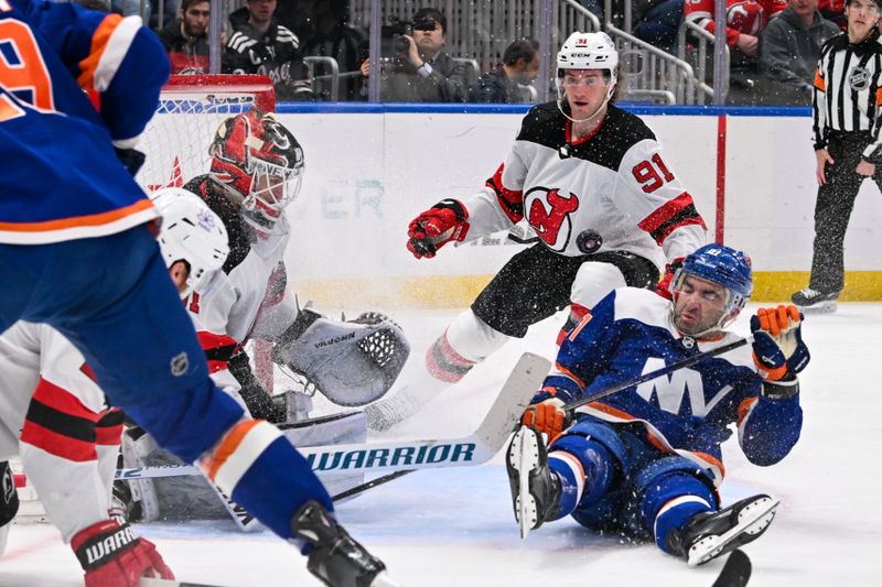 Mar 24, 2024; Elmont, New York, USA;  New York Islanders center Kyle Palmieri (21) falls to the ice in front of New Jersey Devils goaltender Kaapo Kahkonen (31) during the second period at UBS Arena. Mandatory Credit: Dennis Schneidler-USA TODAY Sports