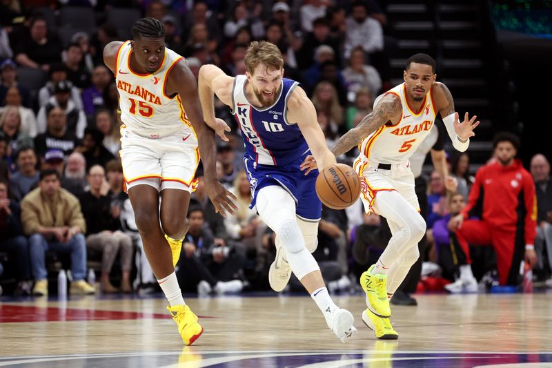 SACRAMENTO, CALIFORNIA - JANUARY 22: Domantas Sabonis #10 of the Sacramento Kings dribbles down court in front of Clint Capela #15 and Dejounte Murray #5 of the Atlanta Hawks in the first half at Golden 1 Center on January 22, 2024 in Sacramento, California. NOTE TO USER: User expressly acknowledges and agrees that, by downloading and or using this photograph, User is consenting to the terms and conditions of the Getty Images License Agreement.  (Photo by Ezra Shaw/Getty Images)