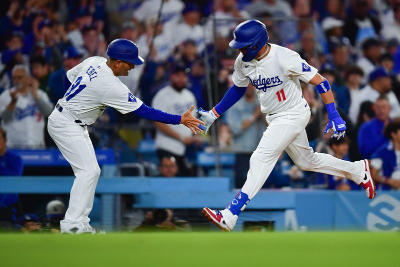 Apr 3, 2024; Los Angeles, California, USA; Los Angeles Dodgers shortstop Miguel Rojas (11) is greeted by third base coach Dino Ebel (91) after hitting a solo home run against the San Francisco Giants during the fourth inning at Dodger Stadium. Mandatory Credit: Gary A. Vasquez-USA TODAY Sports