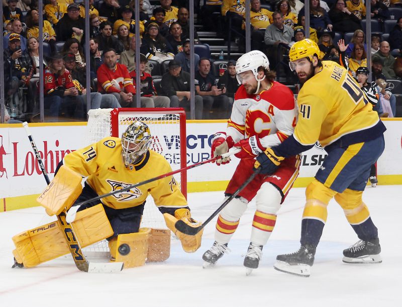 Nov 1, 2025; Nashville, Tennessee, USA; Nashville Predators goalie Juuse Saros (74) anddefenseman Nicolas Hague (41) battle Calgary Flames defenseman Rasmus Andersson (4) for the puck during the second period at Bridgestone Arena. Mandatory Credit: Alan Poizner-Imagn Images