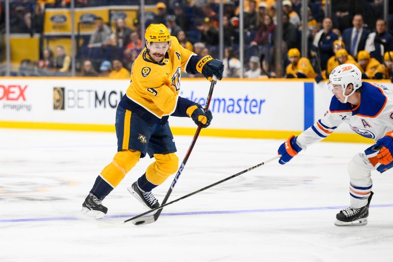 Oct 31, 2024; Nashville, Tennessee, USA;  Nashville Predators left wing Filip Forsberg (9) takes a shot on goal as Edmonton Oilers defenseman Brett Kulak (27) pokes at the puck  during the first period at Bridgestone Arena. Mandatory Credit: Steve Roberts-Imagn Images