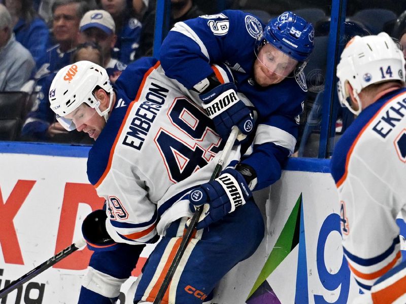 Feb 25, 2025; Tampa, Florida, USA; Tampa Bay Lightning center Jake Guentzel (59) and Edmonton Oilers defensemen Ty Emberson (49) attempt to control the puck in the third period at Amalie Arena. Mandatory Credit: Jonathan Dyer-Imagn Images