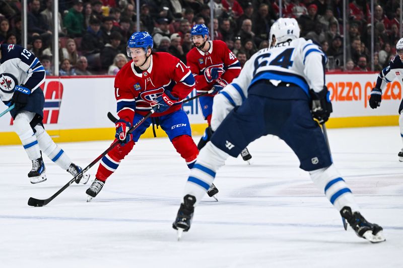 Jan 28, 2025; Montreal, Quebec, CAN; Montreal Canadiens center Jake Evans (71) plays the puck against Winnipeg Jets defenseman Logan Stanley (64) during the second period at Bell Centre. Mandatory Credit: David Kirouac-Imagn Images
