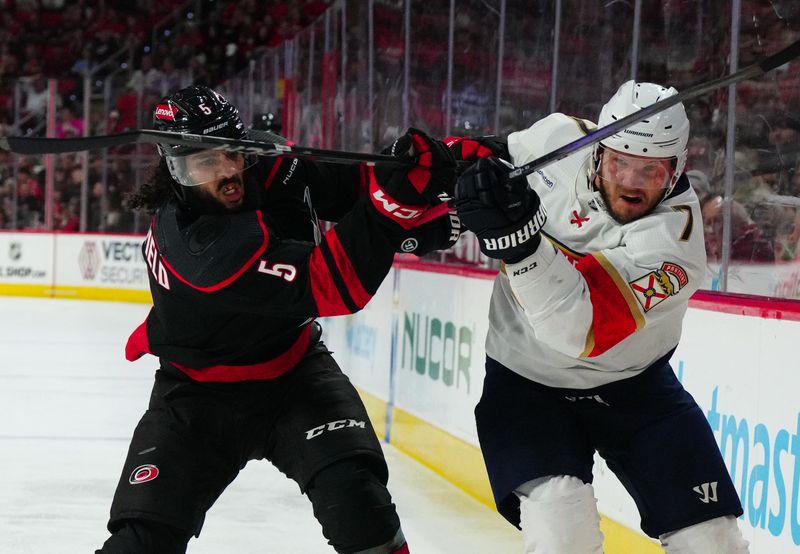 Mar 14, 2024; Raleigh, North Carolina, USA; Carolina Hurricanes defenseman Jalen Chatfield (5) and Florida Panthers defenseman Dmitry Kulikov (7) battle during the second period at PNC Arena. Mandatory Credit: James Guillory-USA TODAY Sports