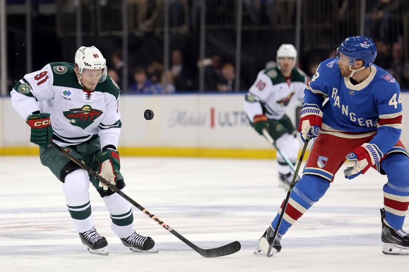 Oct 20, 2025; New York, New York, USA; Minnesota Wild right wing Vladimir Tarasenko (91) fights for the puck against New York Rangers defenseman Vladislav Gavrikov (44) during the first period at Madison Square Garden. Mandatory Credit: Brad Penner-Imagn Images