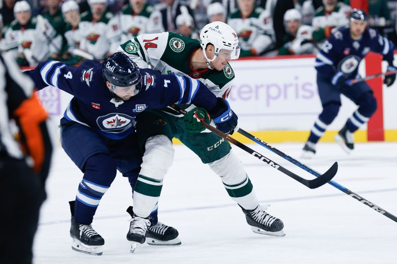 Nov 23, 2025; Winnipeg, Manitoba, CAN;  Minnesota Wild forward Joel Eriksson EK (14) tries to skate away from Winnipeg Jets defenseman Neal Pionk (4) during the first period at Canada Life Centre. Mandatory Credit: Terrence Lee-Imagn Images