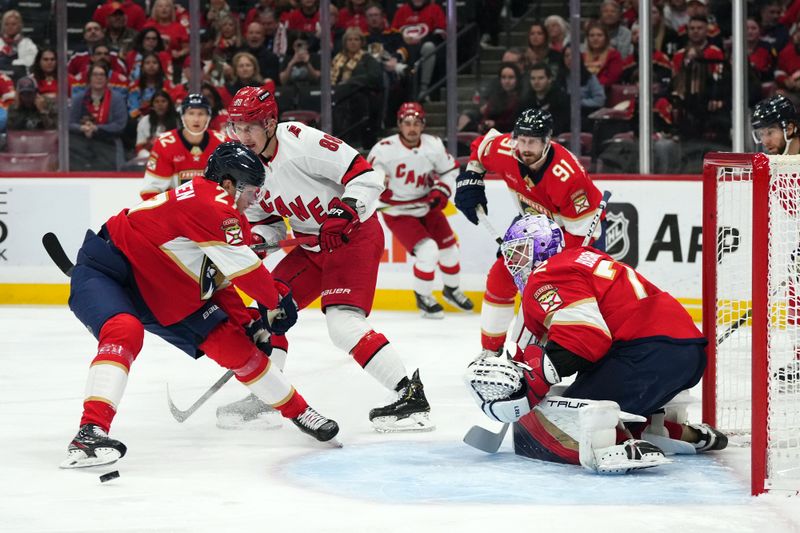 Nov 10, 2023; Sunrise, Florida, USA; Florida Panthers center Eetu Luostarinen (27) deflects the puck away from Carolina Hurricanes center Martin Necas (88) during the first period at Amerant Bank Arena. Mandatory Credit: Jasen Vinlove-USA TODAY Sports