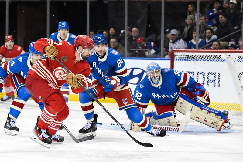 Nov 16, 2025; New York, New York, USA; Detroit Red Wings center Dylan Larkin (71) passes the puck while defended by New York Rangers defenseman Carson Soucy (24) during the second period at Madison Square Garden. Mandatory Credit: John Jones-Imagn Images