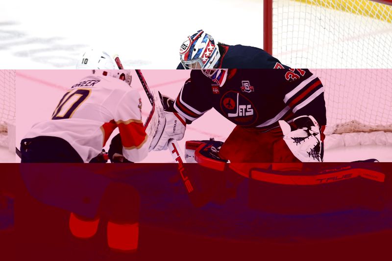 Jan 22, 2026; Winnipeg, Manitoba, CAN; Winnipeg Jets goaltender Connor Hellebuyck (37) blocks a shot from Florida Panthers left wing A.J. Greer (10) in the first period at Canada Life Centre. Mandatory Credit: James Carey Lauder-Imagn Images